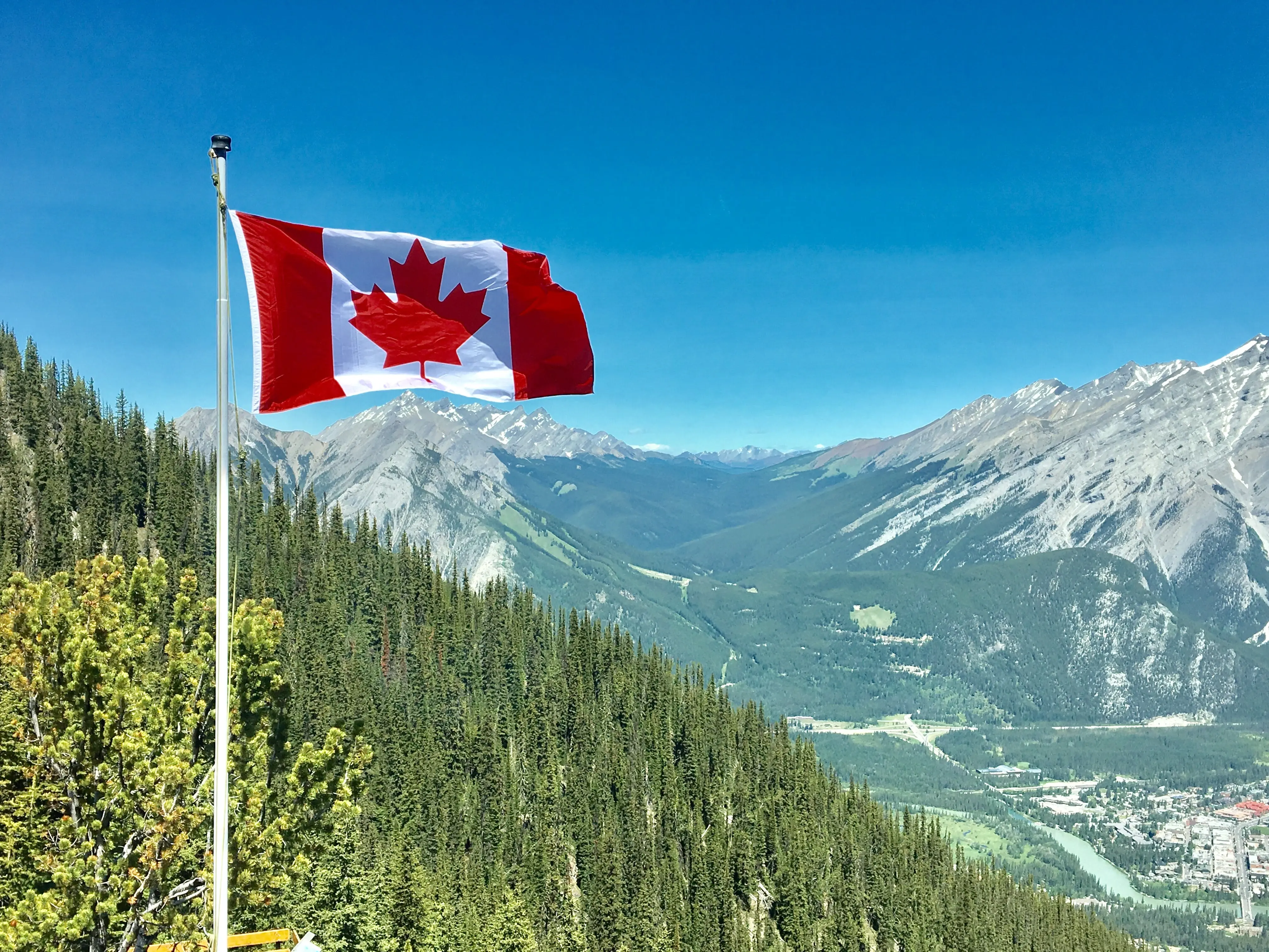 Canadian flag at top of a flag pole, overlooking a mountain range