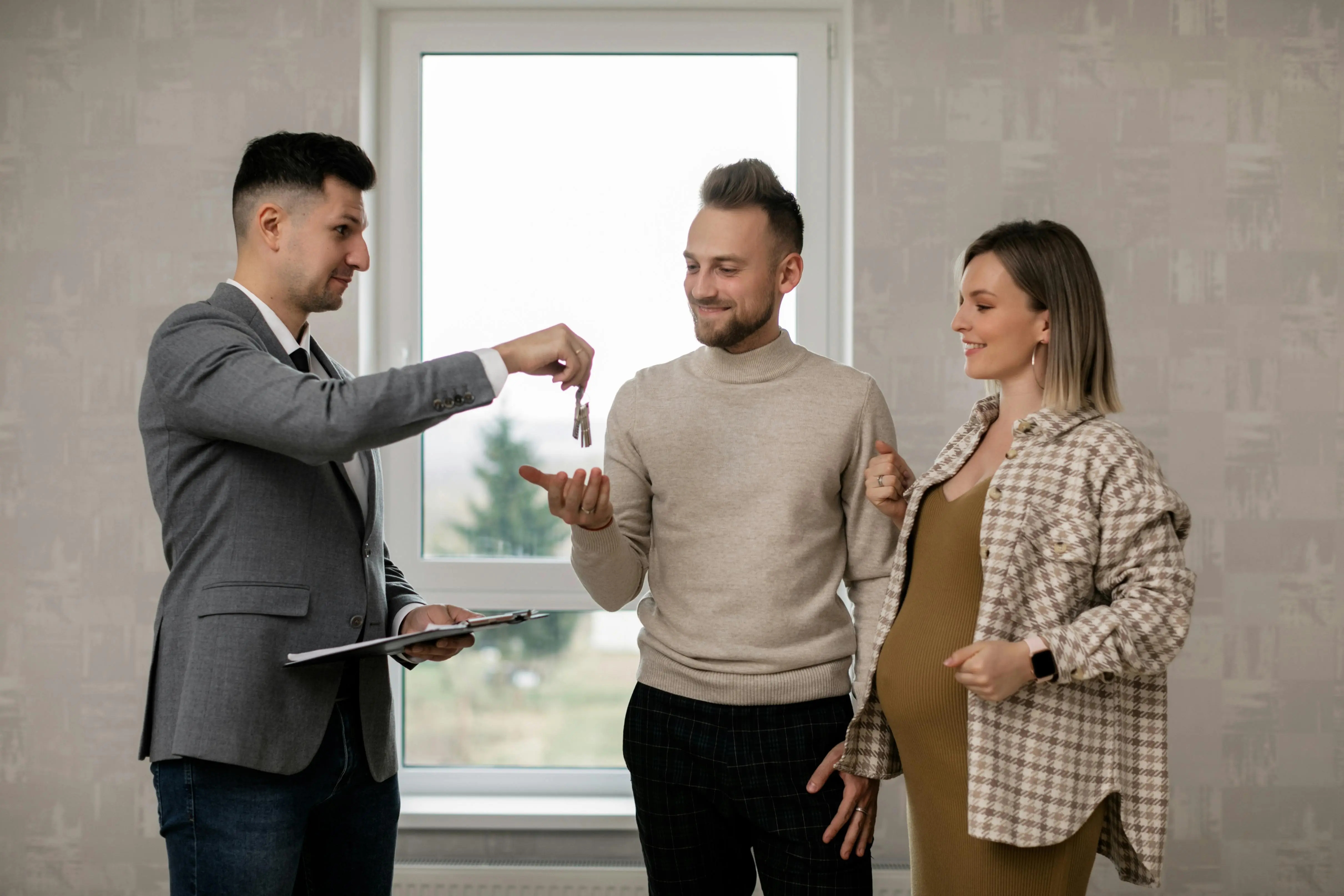 Realtor giving a pair of keys to a young couple
